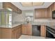 Kitchen featuring neutral countertops, brown cabinetry, tile flooring and black appliances at 1621 Crossridge Dr, Brandon, FL 33510