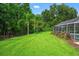 Vast backyard with manicured lawn, mature trees, and a screened-in pool area at 17311 Carriage Way, Odessa, FL 33556