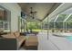 Inviting covered patio with comfortable seating, ceiling fans, and views of the landscaped backyard with a hot tub at 17311 Carriage Way, Odessa, FL 33556