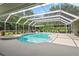A screened-in pool with hot tub and patio seating surrounded by lush landscaping at 17311 Carriage Way, Odessa, FL 33556