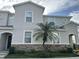 Charming townhome featuring a stone facade, a well-manicured lawn, and a beautiful palm tree at 1941 Greenwood Valley Dr, Plant City, FL 33563