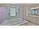Bright bathroom features a large soaking tub and walk-in tiled shower with glass block window at 2535 Regal River Rd, Valrico, FL 33596