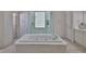 Bright bathroom features a large soaking tub and walk-in tiled shower with glass block window at 2535 Regal River Rd, Valrico, FL 33596