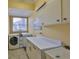 Laundry room with white appliances, ample counter space, and overhead cabinets for efficient organization at 2535 Regal River Rd, Valrico, FL 33596