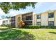 Condo building featuring a screened-in balcony and well-maintained lawn at 3114 Lake Pine Way # H2, Tarpon Springs, FL 34688