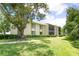 Exterior of a two-story condo building with mature trees and manicured landscaping at 3114 Lake Pine Way # H2, Tarpon Springs, FL 34688
