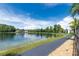 Scenic view of the lake with a walking path and lush greenery on a sunny day at 3114 Lake Pine Way # H2, Tarpon Springs, FL 34688
