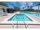 Sparkling pool and jacuzzi with chairs and tables under bright blue sky, surrounded by lush greenery at 3114 Lake Pine Way # H2, Tarpon Springs, FL 34688