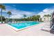 Community pool with seating, mature palm trees, and blue skies at 3114 Lake Pine Way # H2, Tarpon Springs, FL 34688
