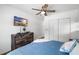 Bedroom featuring wood-look flooring, a modern ceiling fan, a mounted TV, and ample closet space at 3133 Payne St, New Port Richey, FL 34655