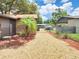 Backyard with rock landscaping, palm trees, and chain link fencing, with a detached garage at 3304 Alamar St, Lutz, FL 33558