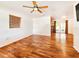 Spacious living room with gorgeous hardwood floors, a ceiling fan, and ample natural light from the window at 3304 Alamar St, Lutz, FL 33558