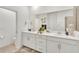 Bathroom vanity featuring dual sinks, white cabinets, a large mirror, and neutral tones at 43250 Water Bird Way # 5921, Punta Gorda, FL 33982