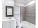 Updated bathroom featuring gray tile, modern fixtures, and a decorative framed mirror at 485 Stillwater Ave, Spring Hill, FL 34606