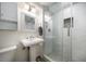 Bathroom features a white pedestal sink, decorative mirror, and tiled glass-enclosed shower at 520 34Th N Ave, St Petersburg, FL 33704