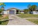 A one-story home with a driveway leading to a gray garage and a yard with various plants at 529 59Th S Way, St Petersburg, FL 33707