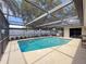 Beautiful screened-in pool features a paved deck and mature landscaping creating a private backyard oasis at 603 Ivey Ln, Tarpon Springs, FL 34689
