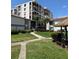 Exterior of a condo community with mature palm trees, a tiki hut, and sidewalk access at 6218 Palma Del Mar # 303, St Petersburg, FL 33715