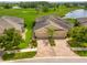 Aerial view of the tan-colored home featuring a red brick driveway, well-kept landscaping, and pond views at 644 Chipper Dr, Sun City Center, FL 33573