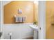 Stylish powder room with pedestal sink, wainscoting, and decorative mirror, providing a convenient and elegant space at 6677 84Th N Ave, Pinellas Park, FL 33781