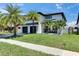 Beautiful home exterior with well-manicured lawn, palm trees, a basketball hoop, and a modern two-car garage at 729 89Th N Ave, St Petersburg, FL 33702