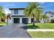 Charming two-story home with a lush front yard, modern garage doors, and a basketball hoop on the driveway at 729 89Th N Ave, St Petersburg, FL 33702