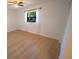 Bright bedroom with wood flooring, white walls, ceiling fan, and window with sheer curtains at 10729 Drummond Rd, Tampa, FL 33615