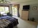 Comfortable bedroom with a desk area, television, and sliding glass doors to a cozy outdoor patio at 110 Lakeside Ct # 110, Oldsmar, FL 34677