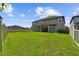 View of a large backyard that has a well-kept green lawn, a privacy fence, and a house at 11002 Sundrift Dr, Tampa, FL 33647