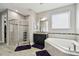 Bright bathroom featuring a soaking tub, a glass shower and a granite-topped vanity with black cabinets at 11002 Sundrift Dr, Tampa, FL 33647
