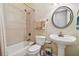 Cozy bathroom with tile shower, pedestal sink, and round mirror, featuring neutral tones and a clean design at 1109 Colson Rd, Plant City, FL 33567