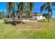 Exterior view of a home's screened-in lanai and back yard, framed by lush palm trees at 1109 Colson Rd, Plant City, FL 33567