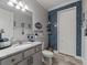 A bathroom with a granite countertop vanity, gray cabinets and blue brick accent wall at 11219 Paddock Manor Ave, Riverview, FL 33569