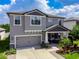 Two-story home featuring a well-manicured lawn, a two-car garage, and a welcoming front porch at 11219 Paddock Manor Ave, Riverview, FL 33569