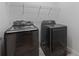 Laundry room featuring modern, high-efficiency front-loading black washer and dryer at 11219 Paddock Manor Ave, Riverview, FL 33569