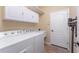 Bright laundry room with white cabinetry, washer, dryer, utility sink and a door to the exterior at 11343 Dancing River Dr, Venice, FL 34292