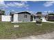 Single-story home with well-kept lawn, mature landscaping, and attached garage at 1144 Rushmore Dr, Holiday, FL 34690