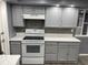 Modern kitchen with sleek gray cabinetry, stainless steel appliances, and stylish backsplash at 1144 Rushmore Dr, Holiday, FL 34690