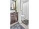 Cozy bathroom with gray rugs, tiled floor, wooden vanity, and shower behind a white curtain at 1250 S Pinellas Ave # 207, Tarpon Springs, FL 34689