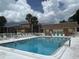 Relaxing community pool area with lounge chairs, surrounded by lush landscaping and beautiful sunny skies at 12760 Indian Rocks Rd # 904, Largo, FL 33774