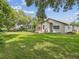 Lush backyard showcasing a well-maintained lawn, mature trees, and a screened-in pool enclosure at 18803 Misty Shores Ln, Lutz, FL 33548