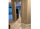 Hallway featuring tile flooring, beige walls, and open entryway leading to a sunlit room at 19239 Stone Hedge Dr, Tampa, FL 33647