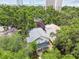 Aerial shot showcases a house surrounded by lush trees, a manicured lawn, and a glimpse of the water in the distance at 2506 S Obrapia St, Tampa, FL 33629