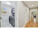 Efficient laundry room with modern washer and dryer, organized shelving and hardwood floors in the hallway at 2506 S Obrapia St, Tampa, FL 33629