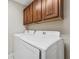 Laundry room with overhead cabinets and modern side-by-side washer and dryer at 25946 Buckthorn Ave, Land O Lakes, FL 34639