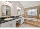 Luxurious bathroom with granite counters, double sinks, a soaking tub, and a decorative window at 3269 Nicks Pl, Clearwater, FL 33761