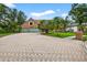 Charming brick home featuring a paved driveway, lush lawn, and mature trees under a sunny sky at 3269 Nicks Pl, Clearwater, FL 33761