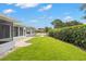 Well-maintained backyard features lush grass, a brick pathway, and a screened-in lanai, perfect for outdoor enjoyment at 3501 Sarazen Dr, New Port Richey, FL 34655