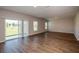 Spacious living room featuring modern wood flooring, ample natural light, and sliding glass doors at 36933 Sagemoor Dr, Zephyrhills, FL 33541