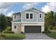 Charming two-story home with a gray and white exterior and a two-car garage, surrounded by lush landscaping at 37092 Sagemoor Dr, Zephyrhills, FL 33541